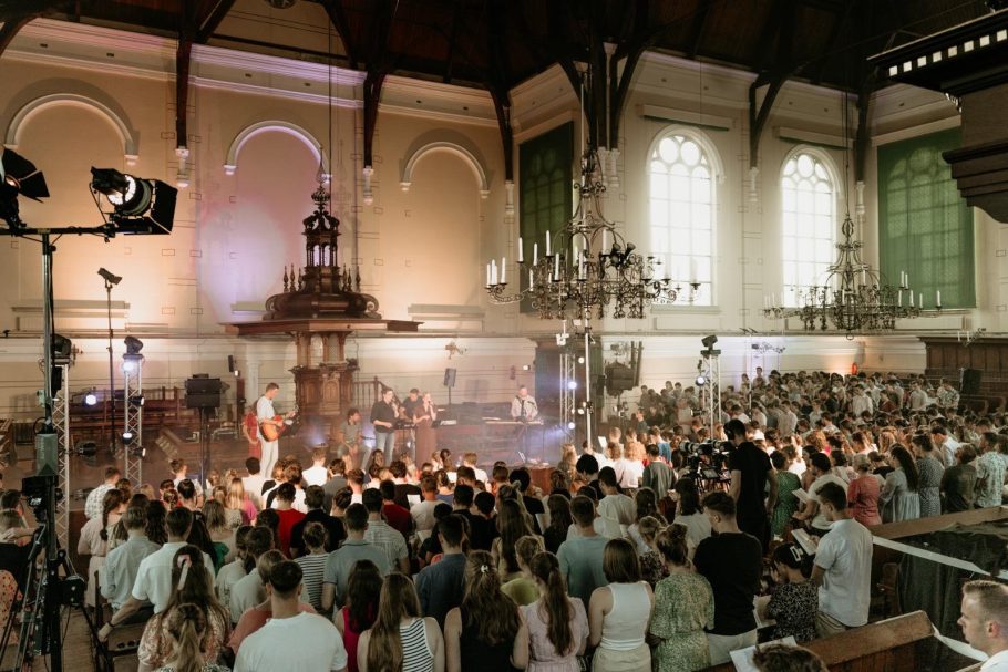 Een drukke zaal met publiek, een podium met muzikanten en sfeervolle verlichting.